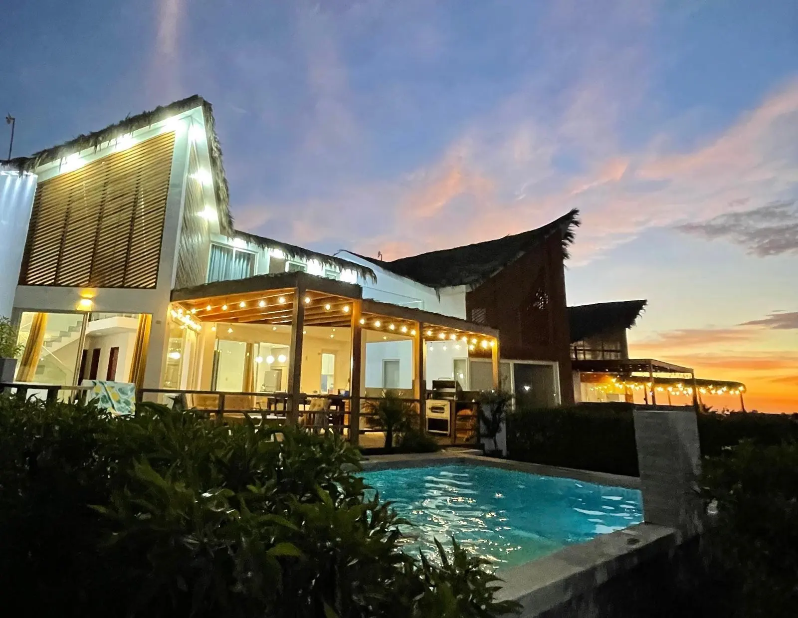 La casa iluminada al atardecer, con la piscina delante